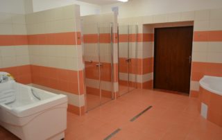 koupelna s oranžovým obložením, sprchovými kouty a masážní vanou