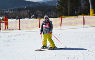 osoba v lyžařské výstroji na lyžích s růžovými hůlkami