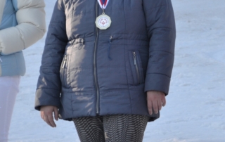 žena stojící na stupni vítězů, okolo krku medaile za první místo