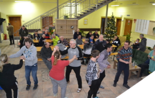 skupina osob tancující v prostorné hale s vánočním stromkem