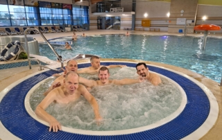 skupina mužů ve vířivce v prostorech krytého bazénu