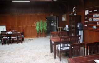 prostorná místnost s dřevem obloženými stěnami, střešními okny a šedou dlažbou vybavená dřevěnými stoly a židlemi v tmavém odstínu